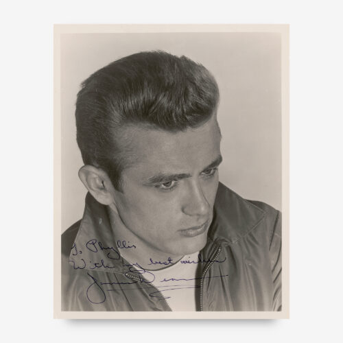 Iconic glossy 8 x 10 photo of the brooding young actor wearing a zippered jacket and white t-shirt resembling those from Rebel Without a Cause, boldly signed and inscribed in fountain pen, "To Phyllis, With my best wishes, James Dean."